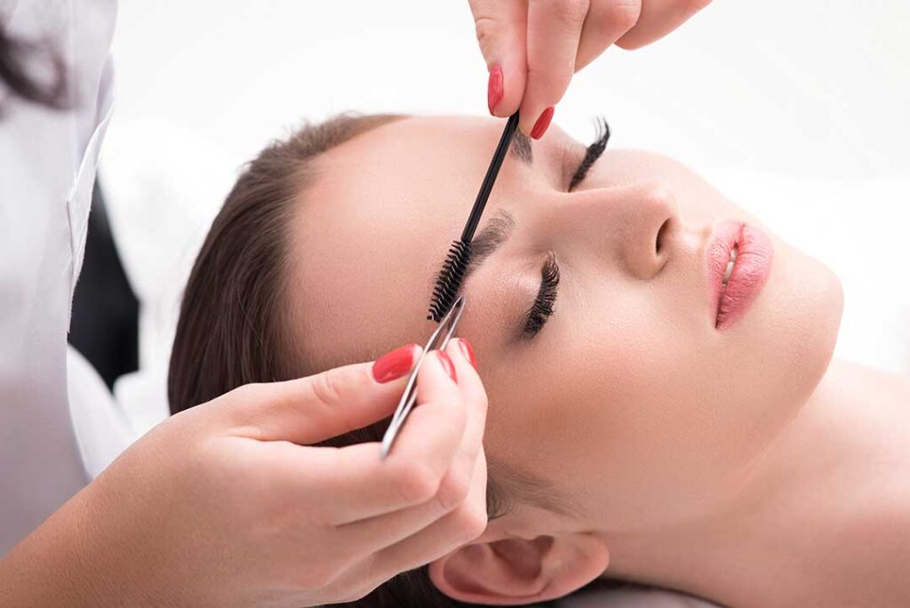 A woman gently washing her face at home, looking into the bathroom mirror with a calm expression.